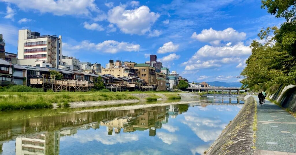 鴨川沿いの遊歩道と水面に映る京都市街地の風景